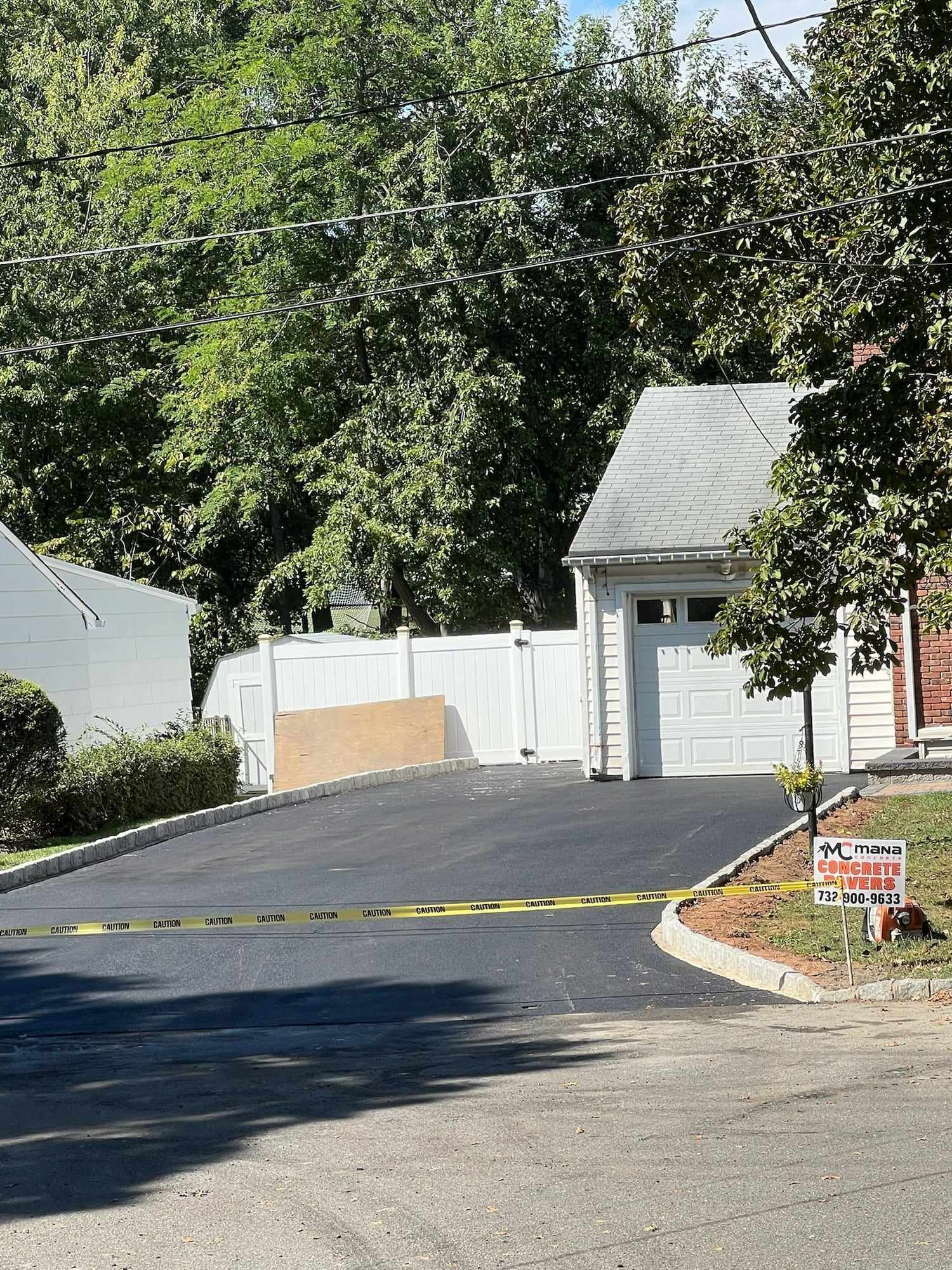 Freshly paved asphalt driveway leading to a detached garage in a New Jersey neighborhood