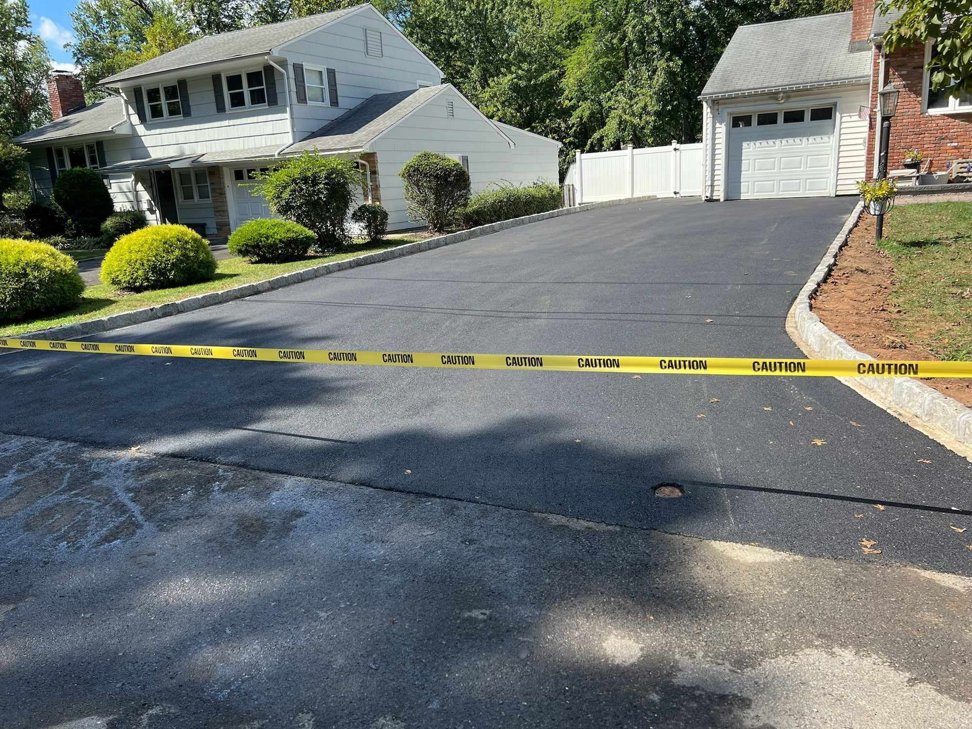 New black asphalt driveway in front of a ranch home and garage in New Jersey