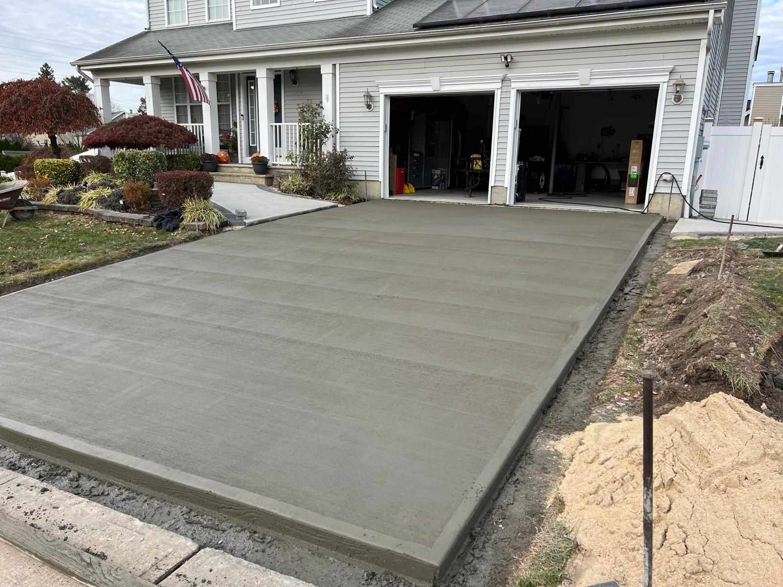 Fresh concrete driveway with a smooth broom finish ahead of a two-car garage in New Jersey