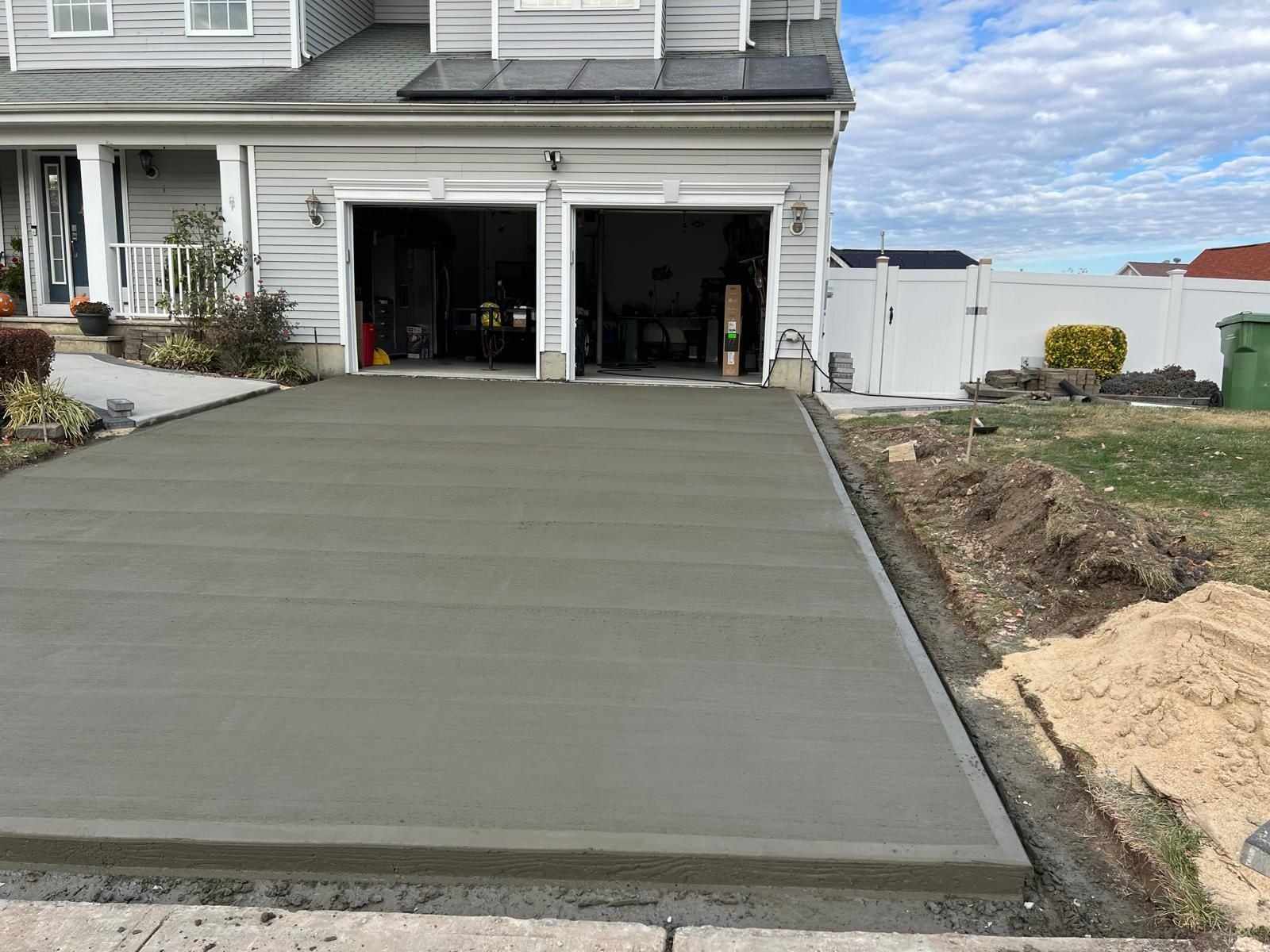 Newly poured concrete driveway in front of a two-car garage in New Jersey