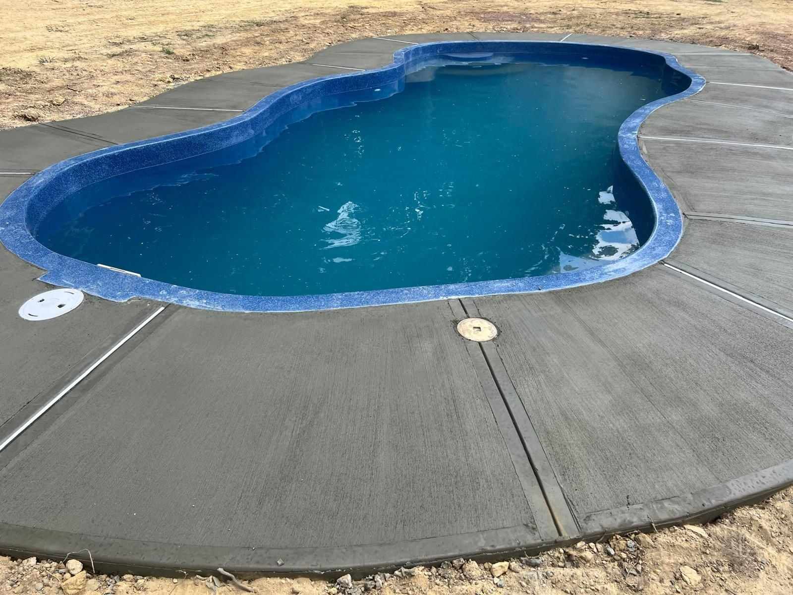 Fresh broom-finished concrete pool deck with control joints around a freeform pool in New Jersey