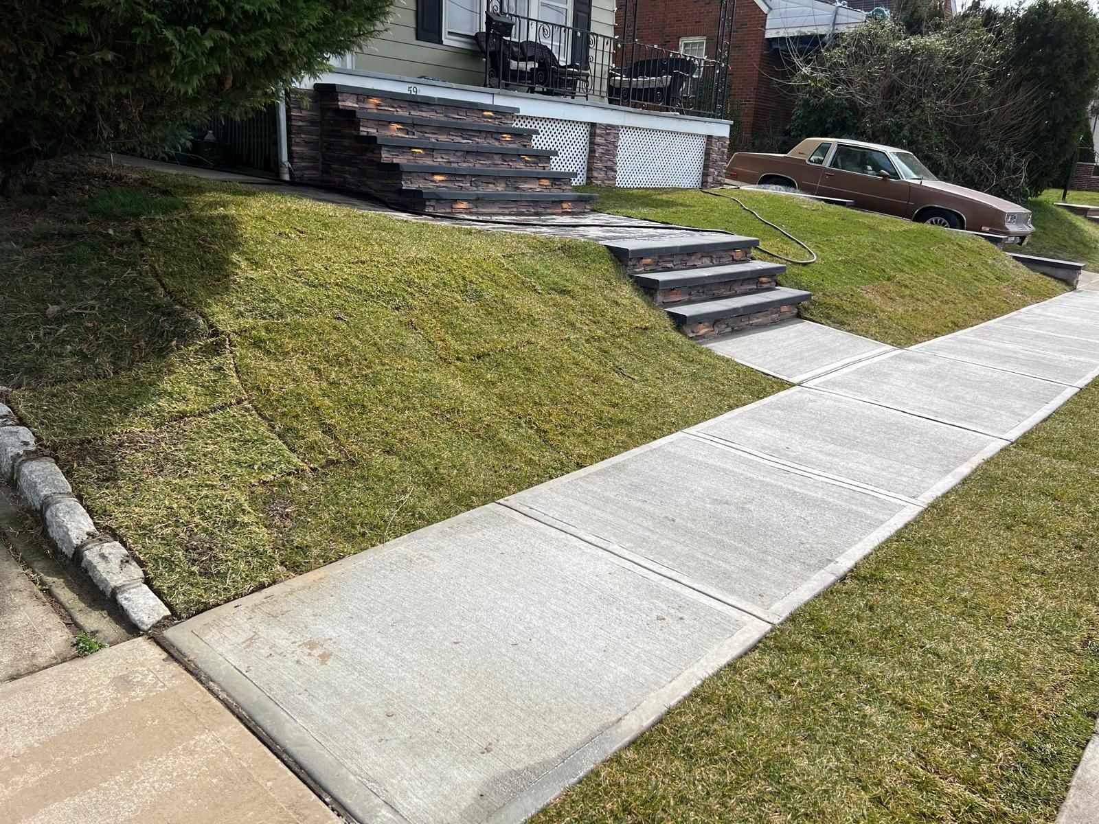 New concrete sidewalk with Belgian block curbing and front steps on a sloped New Jersey lawn