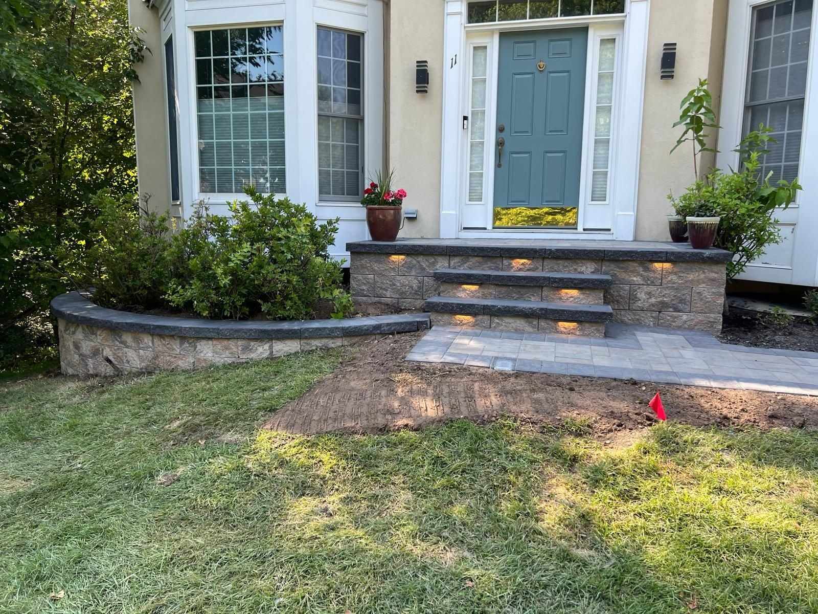 Front steps with lights and a curved garden wall planted with shrubs at a New Jersey home
