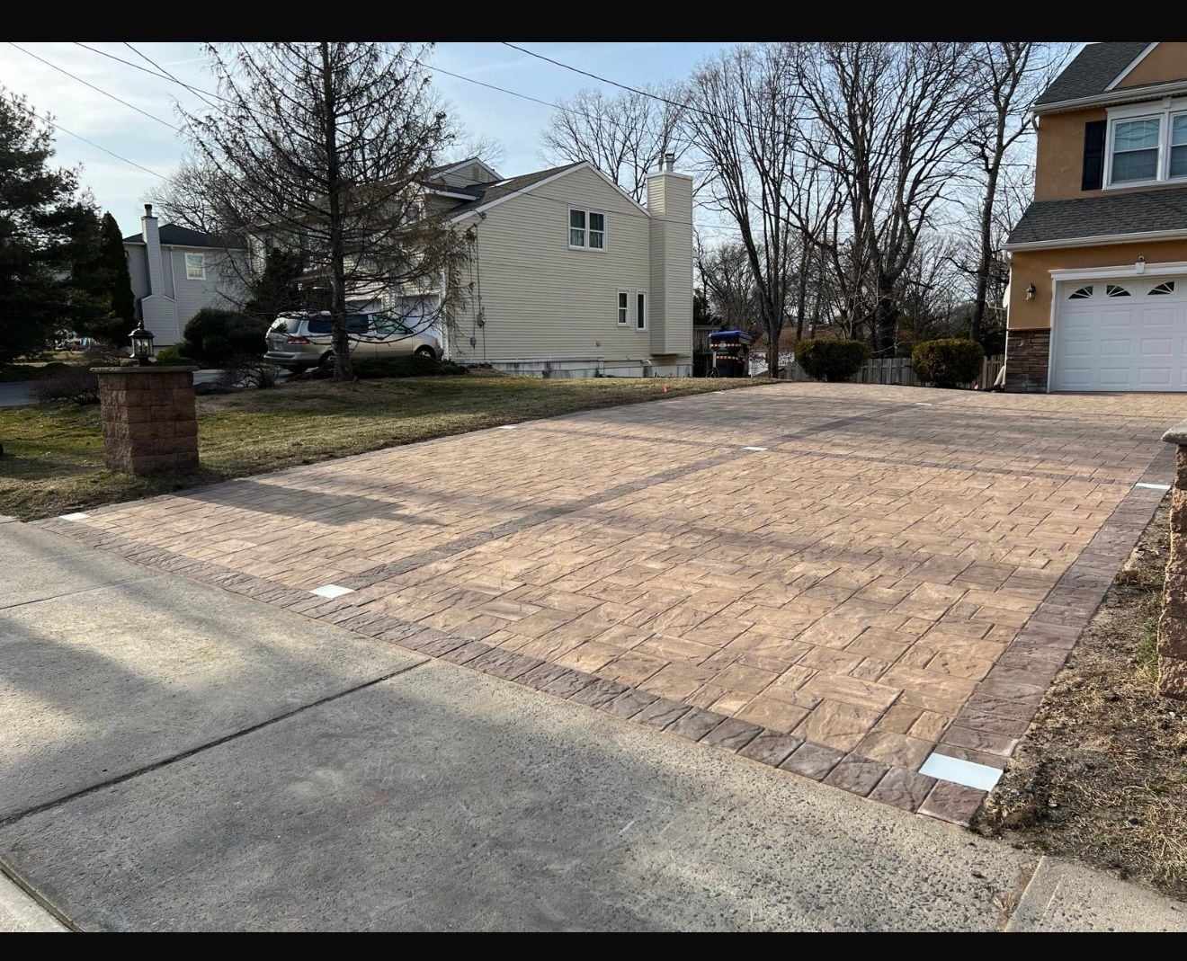 Red-tone herringbone paver driveway with a darker border in a New Jersey neighborhood