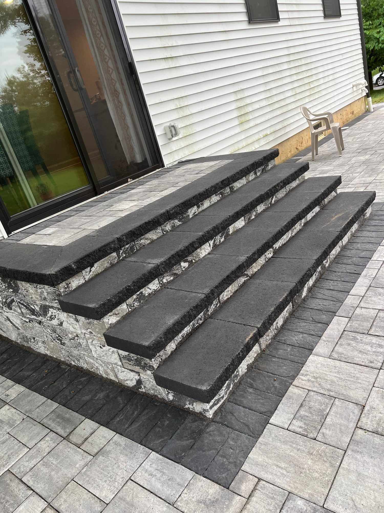 Dark paver steps with stone-veneer risers leading to a sliding door in New Jersey