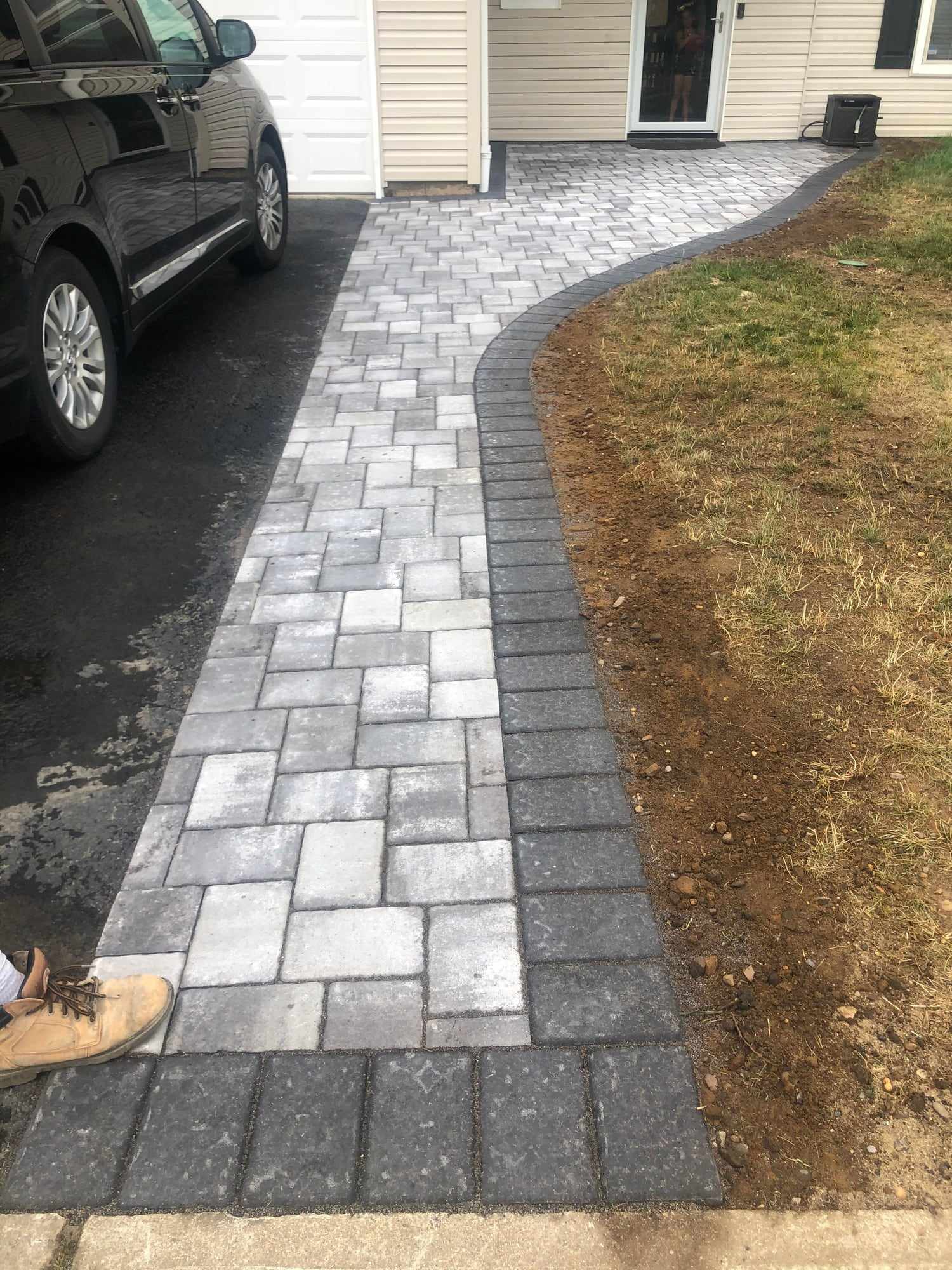 Gray paver walkway with charcoal border curving beside an asphalt driveway in New Jersey