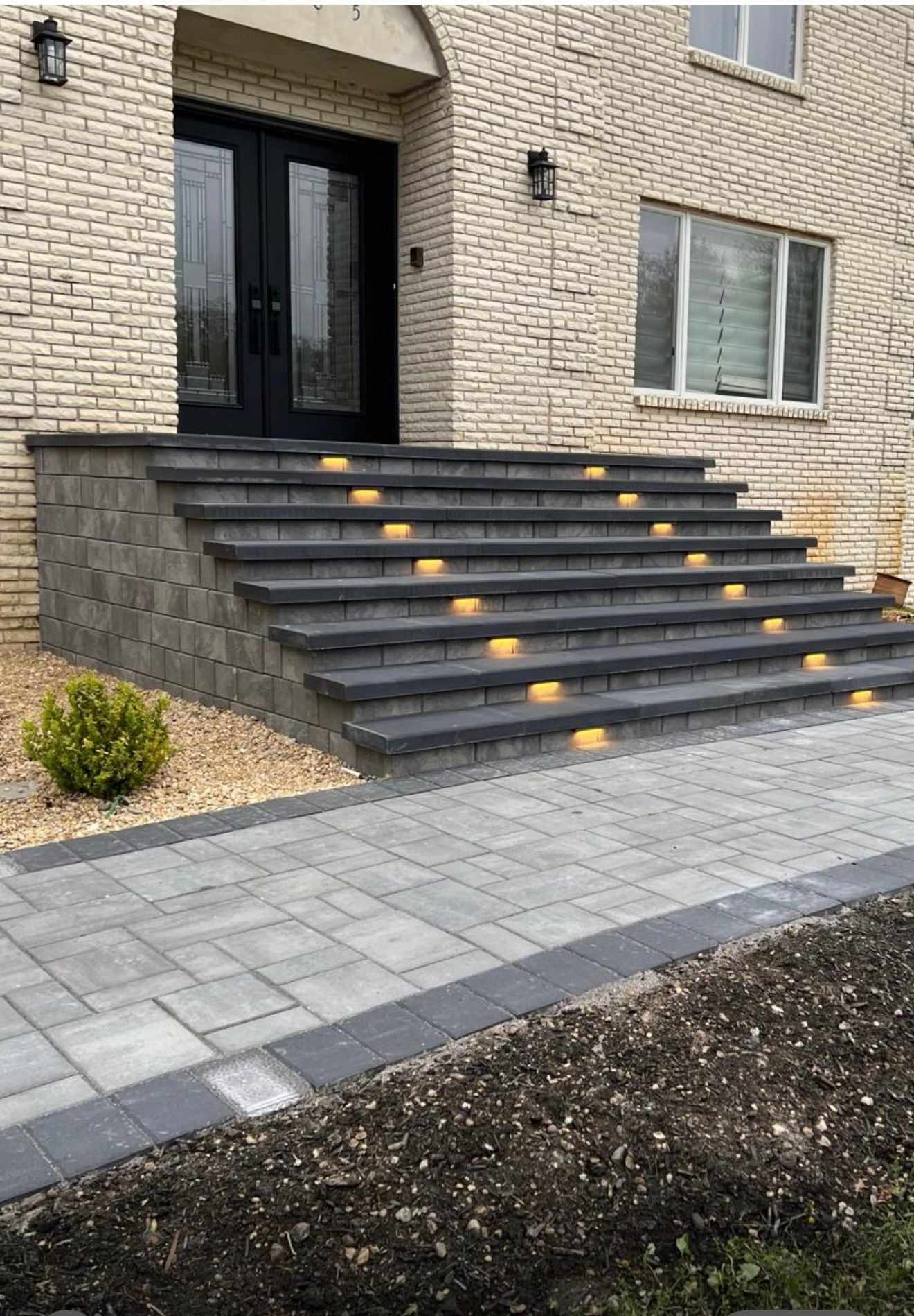 Wide paver front entry steps with built-in lights and a paver walkway at a brick New Jersey home
