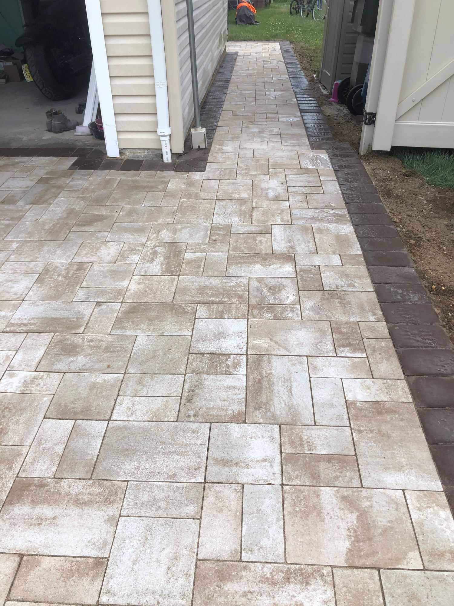 Light paver walkway with a dark border along the side of a New Jersey house